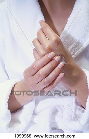 Stock Photo - Close-Up Of A Woman Applying Lotion To Her Hands, White Robe C1209. Fotosearch
