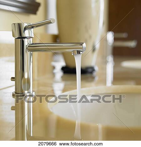 Close Up Of Bathroom Faucet With Running Water And Marble