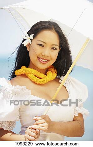Stock Photo - Close-Up Of Beautiful Hawaiian Holding White Umbrella Wearing White Dress And Yellow Lei. Fotosearch