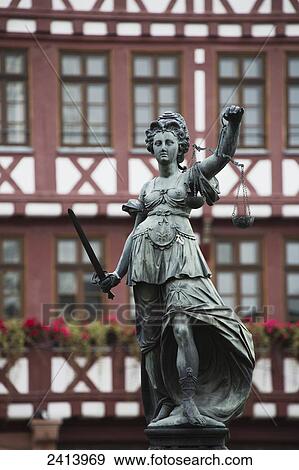 Close up of bronze female statue with sword and scale against tudor style buildings in the background; Frankfurt am Main, Germany View Large Photo Image Stock Photo - Close up of bronze female statue with sword and scale against tudor style buildings in the background; Frankfurt am Main, Germany. Fotosearch
