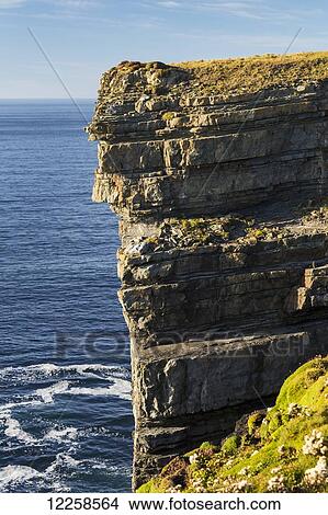 Close up of cliffs along the water's edge and blue sky; Kilkee, County Clare, Ireland View Large Photo Image Picture - Close up of cliffs along the water's edge and blue sky; Kilkee, County Clare, Ireland. Fotosearch