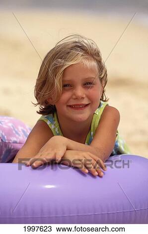 Stock Image - Close-Up Of Girl On Beach, Leaning Over Purple Inner Tube. Fotosearch
