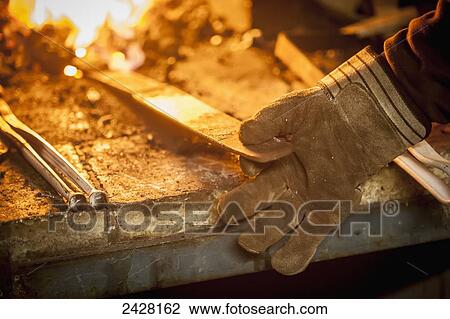 Close up of gloved hand of blacksmith holding metal near fire; Frederick, Maryland, United States of America View Large Photo Image Stock Image - Close up of gloved hand of blacksmith holding metal near fire; Frederick, Maryland, United States of America. Fotosearch