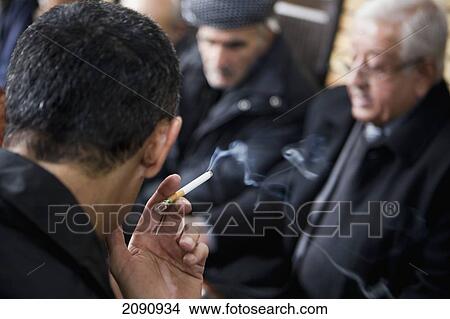 Picture - Close-Up Of Man Smoking With Senior Men In The Background At The Sha'ab Chai Khana [Teahouse], Sulaymaniyah, Iraqi Kurdistan, Iraq. Fotosearch
