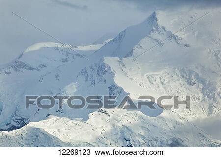 Stock Image - Close up of ridge on Mt. McKinley through thin clouds, Denali National Park and Preserve, Interior Alaska; Alaska, United States of America. Fotosearch