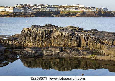 Close up of rocky water's edge reflecting off tranquil water with coastal village in the background; Kilkee, County Clare, Ireland View Large Photo Image Stock Image - Close up of rocky water's edge reflecting off tranquil water with coastal village in the background; Kilkee, County Clare, Ireland. Fotosearch