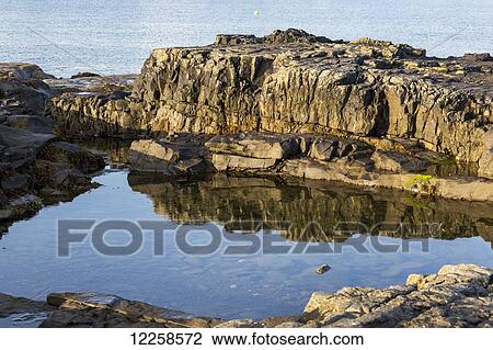 Close up of rocky water's edge reflecting off tranquil water with bay in the background; Kilkee, County Clare, Ireland View Large Photo Image Stock Image - Close up of rocky water's edge reflecting off tranquil water with bay in the background; Kilkee, County Clare, Ireland. Fotosearch