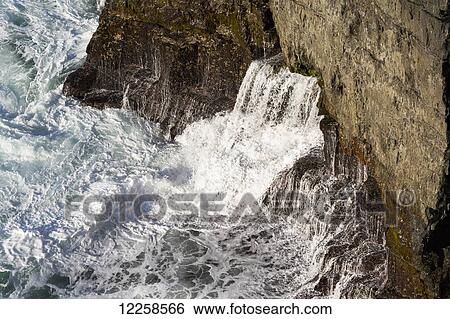 Close up of waves crashing the rocky cliffs creating a waterfalls; Kilkee, County Clare, Ireland View Large Photo Image Stock Photograph - Close up of waves crashing the rocky cliffs creating a waterfalls; Kilkee, County Clare, Ireland. Fotosearch
