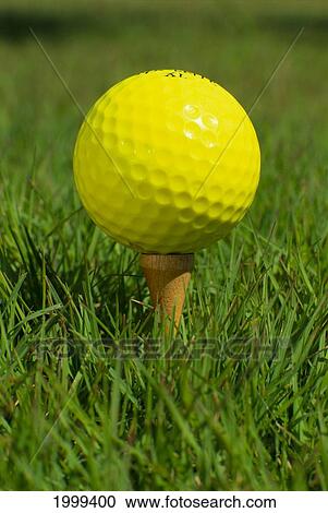 Stock Image - Close-Up, Yellow Golf Ball On Tee In Grass. Fotosearch