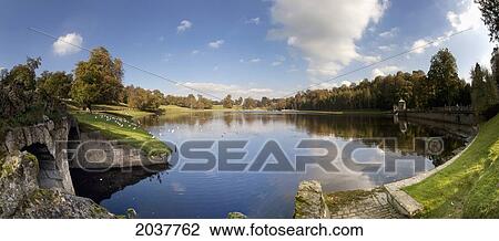 Stock Image - Clouds And Trees Reflected In The Tranquil Water; Studley North Yorkshire England. Fotosearch