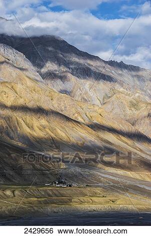Stock Photograph - Clouds cast shadows on the himalayan mountains; Spiti Valley, India. Fotosearch