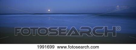 Stock Photo - Coastal Scenic, Full Moon Setting Over Tranquil Blue Ocean, Beach, Panoramic. Fotosearch