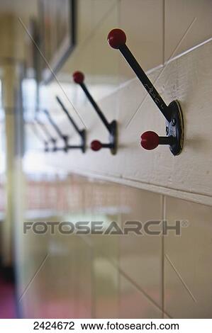 Stock Image - Coat hooks mounted on a wall; London, England. Fotosearch