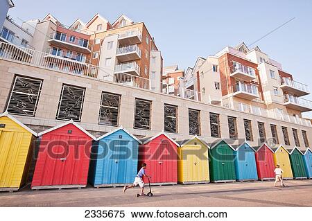 Stock Photography - Colorful Beach Huts And Modern Apartments At Honeycombe Beach Next To Boscombe Pier In Boscombe; Bournemouth, Dorset, England, Uk. Fotosearch