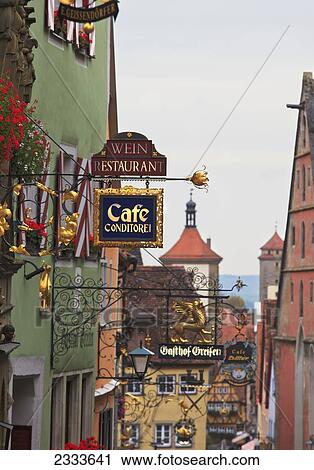 Stock Image - Colorful Sign Ornaments On Top Of Each Shop Or Restaurant; Rothenburg Ob Der Tauber, Bavaria, Germany. Fotosearch