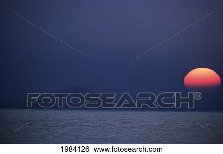 Stock Photograph - Colorful Sun Rising Over Hazy Lake.. Fotosearch