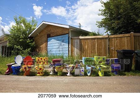 Stock Photo - Colourful And Decorated Toilets Lined Up On The Side Of The Road Outside A House; Spruce Grove Alberta Canada. Fotosearch