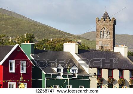 Stock Photo - Colourful houses with stone church steeple, grassy hills and blue sky in background; Dingle, County Kerry, Ireland. Fotosearch