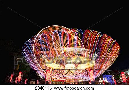 Stock Photography - Colourful Lights Blurring On Amusement Park Rides At Night; Locarno, Ticino, Switzerland. Fotosearch