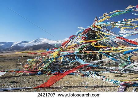 Stock Photo - Colourful Tibetan prayer flags (Lung ta) under the strong wind with white mountain tops in the background; Qinghai province, Tibet. Fotosearch