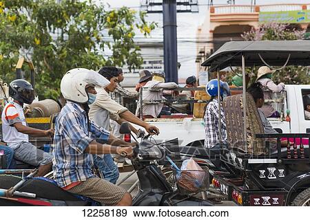 Stock Photo - Commuters on motorcycles on the busy street outside Luh Market; Siem Reap, Cambodia. Fotosearch