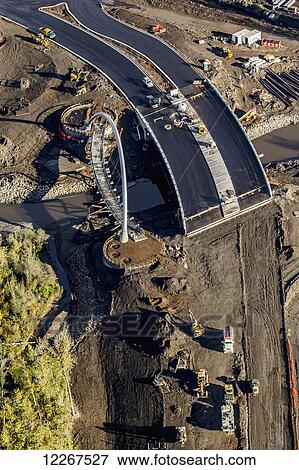 Stock Photo - Construction crew using heavy equipment and engineering technology to install a new bridge as part of the growing road infrastructure; Fort McMurray, Alberta, Canada. Fotosearch
