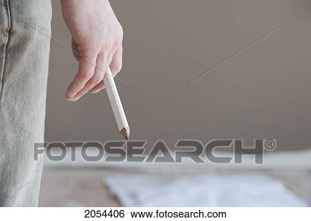 Stock Photograph - Contractor Holding Carpenter Pencil With Blue Prints Sitting On The Floor In The Background, Ontario. Fotosearch