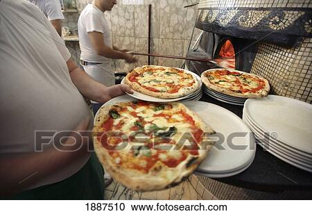 Stock Image - Cooks Making Pizzas In Pizzeria. Fotosearch