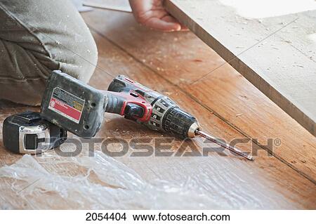 Cordless Drill Lying On The Floor Next To A Measuring Tape, Ontario View Large Photo Image Picture - Cordless Drill Lying On The Floor Next To A Measuring Tape, Ontario. Fotosearch