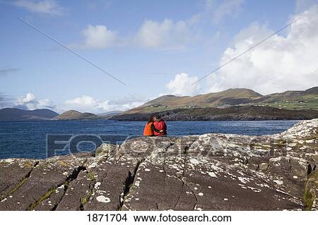 County Kerry, Ireland; A Couple Sits Overlooking The Water Near Caherdaniel View Large Photo Image Picture - County Kerry, Ireland; A Couple Sits Overlooking The Water Near Caherdaniel. Fotosearch
