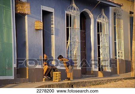 Couple and boy looking at caged bird by blue building; Trinidad, Cuba View Large Photo Image Stock Image - Couple and boy looking at caged bird by blue building; Trinidad, Cuba. Fotosearch