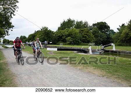 Couple Cycling Beside The Kennet And Avon Canal In Caen Hill, Near Devizes, Wiltshire, Uk View Large Photo Image Stock Image - Couple Cycling Beside The Kennet And Avon Canal In Caen Hill, Near Devizes, Wiltshire, Uk. Fotosearch