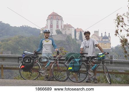 Stock Photo - Couple Cycling With Vranov Chateau In The Background. Fotosearch