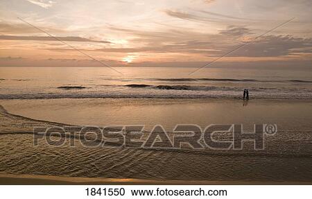 Stock Image - Couple Enjoying Sunset On Beach In Kerala; Arabian Sea, Kerala, India. Fotosearch