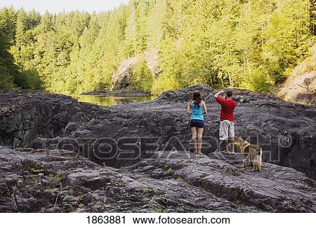 Stock Image - Couple Enjoying The View, Elk Falls; British Columbia, Canada. Fotosearch