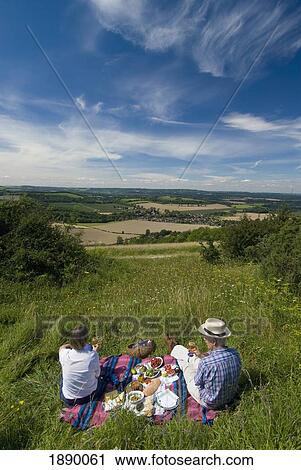 Stock Image - Couple Having Picnic In Meadow On The South Downs, High Angle View. Fotosearch