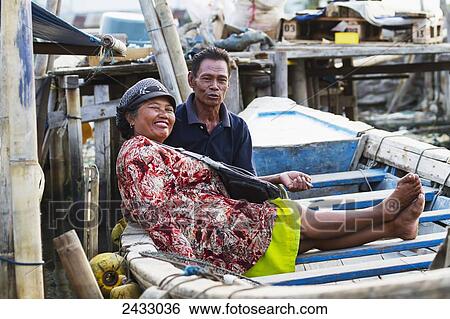 Stock Photograph - Couple in a boat in Sunda Kelapa Harbour, Jakarta, Java, Indonesia. Fotosearch