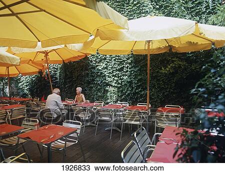 Stock Image - Couple In Garden Restaurant. Fotosearch