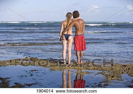Couple In Swimwear Embracing Looking At Ocean At Praia Do Forte, Bahia, Brazil View Large Photo Image Picture - Couple In Swimwear Embracing Looking At Ocean At Praia Do Forte, Bahia, Brazil. Fotosearch