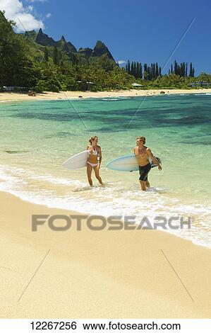 Stock Photograph - Couple in water with bodyboards; Kauai, Hawaii, United States of America. Fotosearch