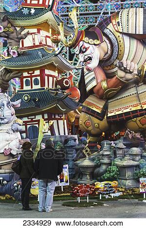 Stock Photo - Couple Looking At Large Falla Of Japanese Warrior Displayed On Street As Part Of Fallas Festival; Valencia, Spain. Fotosearch