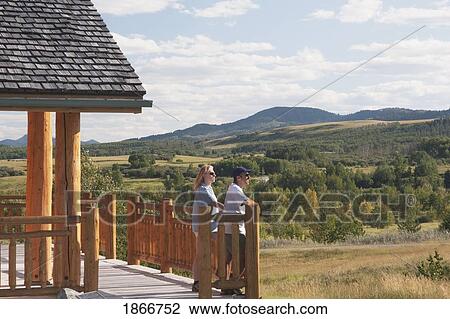 Stock Image - Couple Looking Out At The Hills. Fotosearch