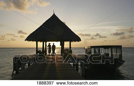 Stock Photo - Couple On Pier Watching The Sunset.. Fotosearch