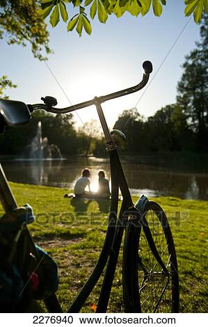 Couple relaxing beside lake in the Vondelpark in the evening; Amsterdam, Holland View Large Photo Image Stock Image - Couple relaxing beside lake in the Vondelpark in the evening; Amsterdam, Holland. Fotosearch