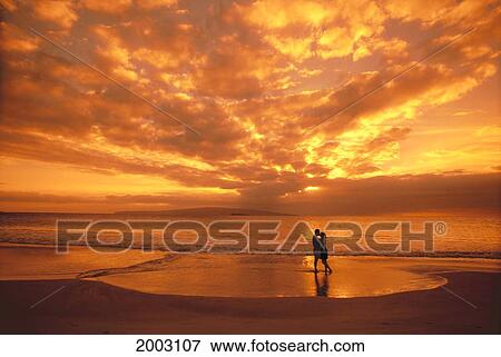 Couple Silhouetted On The Beach During Sunset, Fiery Orange Sky, Clouds View Large Photo Image Stock Photo - Couple Silhouetted On The Beach During Sunset, Fiery Orange Sky, Clouds. Fotosearch