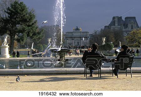 Stock Image - Couple Sitting In Front Of Fountain In Tuileries Gardens. Fotosearch