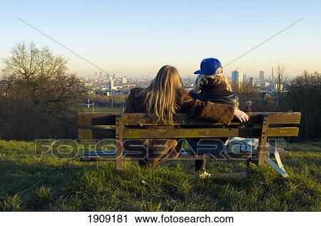 Stock Image - Couple Sitting On Bench On Parliament Hill, Hamstead Heath, London, Uk. Fotosearch