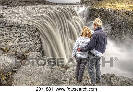 Couple Standing By Dettifoss Waterfall, Iceland View Large Photo Image Stock Image - Couple Standing By Dettifoss Waterfall, Iceland. Fotosearch