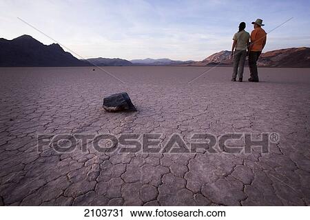Couple Standing Near Moving Rocks At Racetrack Playa; Death Valley California United States Of America View Large Photo Image Stock Image - Couple Standing Near Moving Rocks At Racetrack Playa; Death Valley California United States Of America. Fotosearch