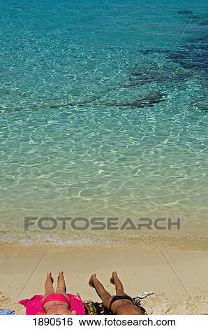 Stock Photograph - Couple Sunbathing At Blue Lagoon Beach. Fotosearch